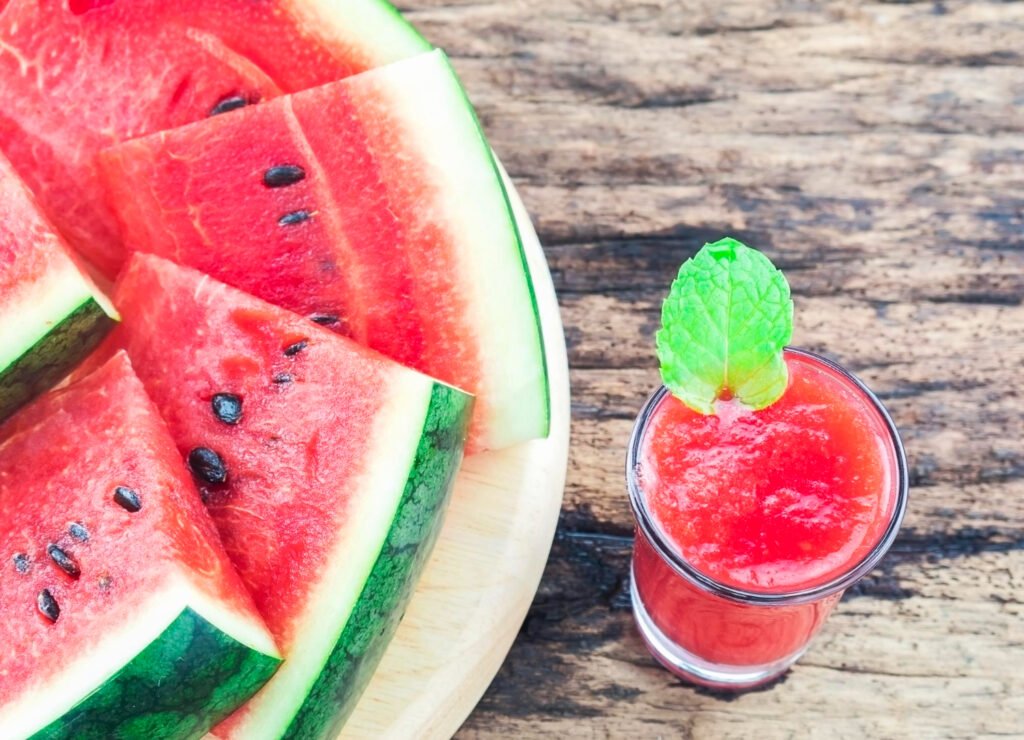 rebanadas de sandia a lado de un vaso de agua de sandia