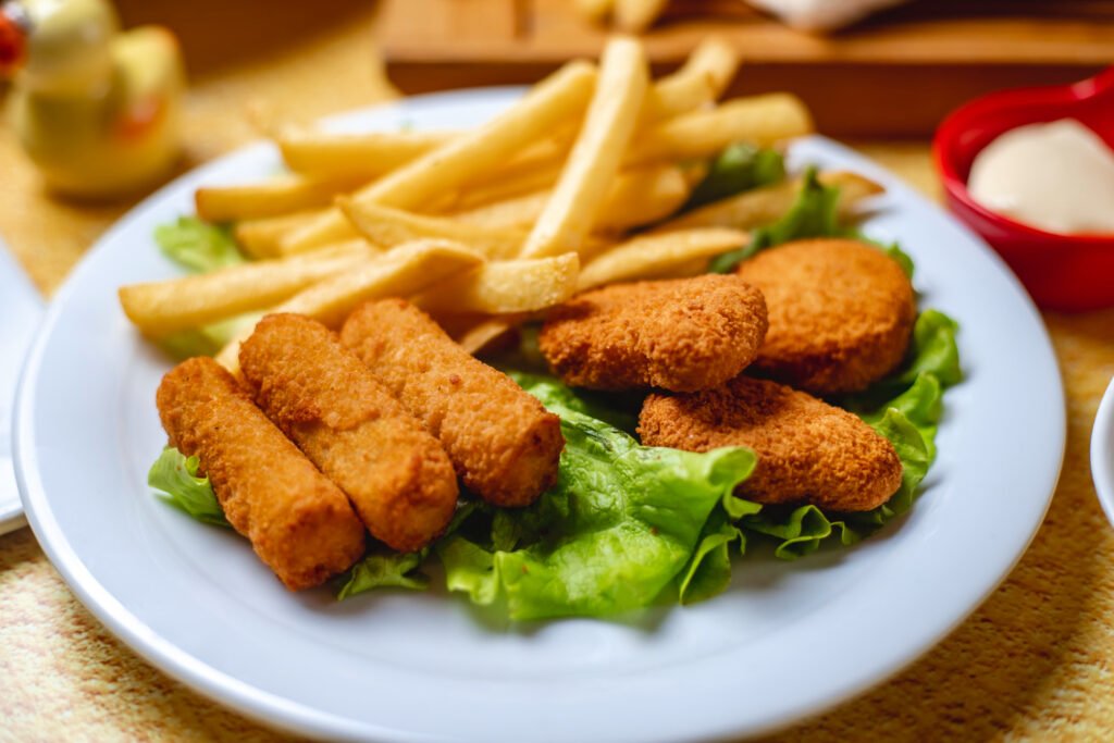 papas fritas con nuggets sobre una cama de lechuga, sobre un plato blanco.