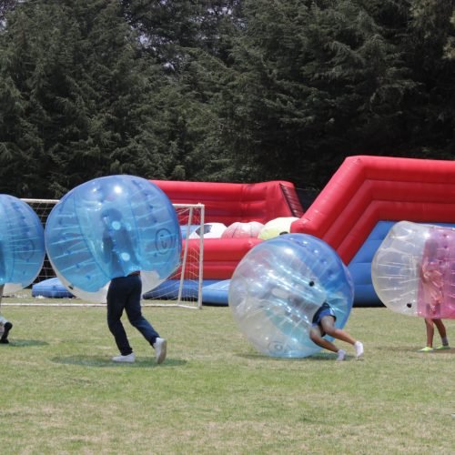 personas jugando con bubble soccer en amplio jardin